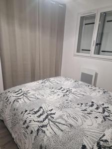 a black and white bed in a white bedroom at La Maison de Coco in Le Puy