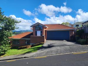 a brick house with a garage in a street at Incredible Waitakere View in Auckland