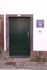 a green garage door on the side of a building at Apartamentos Ázera - António Ázera in Praia da Vitória