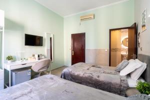 a room with two beds and a desk and a television at CARLO ALBERTO GUESTHOUSE - close to CENTRAL STATION in Rome