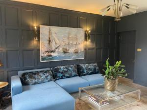 a living room with a blue couch and a painting at Escape to Ash House 18th Century Manor in Somerset in Martock