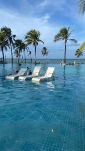 una piscina con sillas y palmeras en el agua en Wai Wai Eco Residence na Praia de Cumbuco en Cumbuco