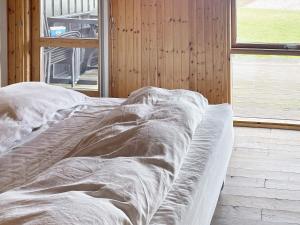 uma cama com um cobertor num quarto com uma janela em Holiday home Præstø II em Praesto