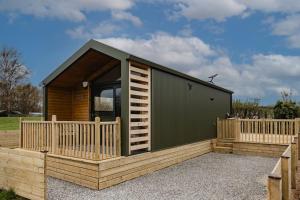 a small cabin with a deck and a fence at Lowfield Lodge & Hot Tub - Humberston Fitties Beach in Cleethorpes