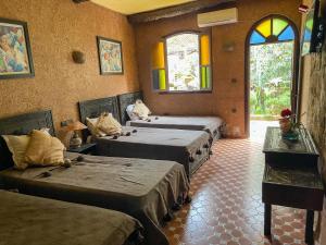 a room with four beds in a room with windows at Auberge le Refuge in Agadir