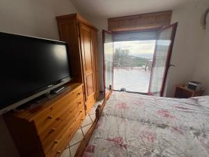 um quarto com uma televisão de ecrã plano e uma cama em Villa del sole em Magomadas