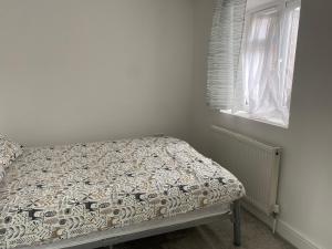 a small bedroom with a bed with a comforter and a window at Your perfect place of comfort in Goodmayes