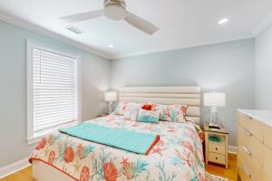 Un dormitorio con una cama y un ventilador de techo. en Seabirds, en Sunset Beach