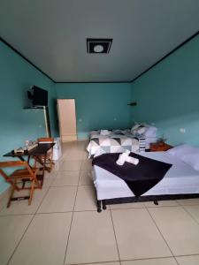 1 dormitorio con 2 camas, mesa y TV en Pousada Love Piri, en Pirenópolis