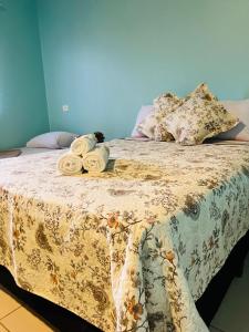 Una cama con una manta con flores y toallas. en Pousada Love Piri, en Pirenópolis