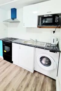 a kitchen with a washing machine and a microwave at Modern Luxurious New Build Entire 2 Bedroom Apartment in Basildon