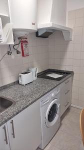 a kitchen with a washing machine and a sink at Cozy Studio - 5 minutos a pé da praia in Costa da Caparica