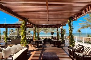 an outdoor patio with tables and chairs and the ocean at Apto Luxo 2 quartos no Solar Tambaú in João Pessoa