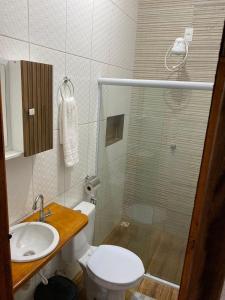 a bathroom with a shower and a toilet and a sink at Pousada Alves e Almeida in Cayru