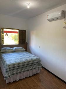 a bedroom with a bed with a window and a fan at Pousada Alves e Almeida in Cairu