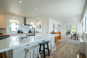 a kitchen with a large white counter and stools at Wanaka Entertainer in Wanaka +20 photos