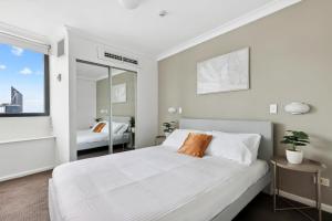 a white bedroom with a large bed and a mirror at 1-Bed Brisbane City Pad with Sweeping Views in Brisbane