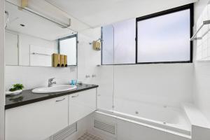 a white bathroom with a sink and a window at 1-Bed Brisbane City Pad with Sweeping Views in Brisbane