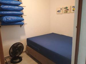 een kamer met een blauw bed en een ventilator bij Apartamento Ubatuba Condominio Maranduba Ville II in Ubatuba