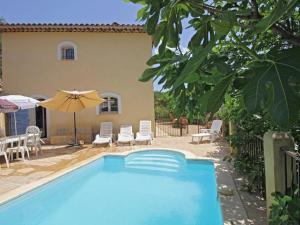 einem Pool mit Stühlen und einem Sonnenschirm neben einem Haus in der Unterkunft Maison Jaune in Cotignac