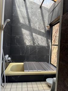 ein Bad mit einer Badewanne und einer schwarzen Wand in der Unterkunft ペットと泊まれるロフト付建物｜CHILL SWING チビ in Nasu