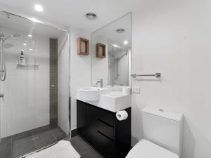 a bathroom with a toilet and a sink and a shower at Discover urban bliss in our 1-bedroom King bed apartment! City views and cultural gems in Brisbane +8 photos