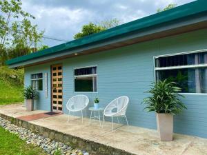 dos sillas y una mesa frente a una casa azul en Hermosa Casa de Campo en Cachí de Cartago con WIFI, en Cachí