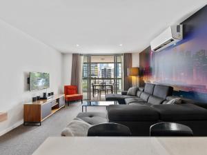 a living room with couches and a tv at Discover urban bliss in our 1-bedroom King bed apartment! City views and cultural gems in Brisbane