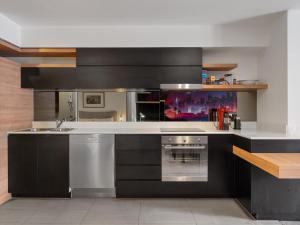 a kitchen with black cabinets and a white counter top at Discover urban bliss in our 1-bedroom King bed apartment! City views and cultural gems in Brisbane
