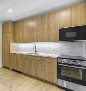 a kitchen with wooden cabinets and a sink and a stove at Newly renovated massive three bedroom! in New York