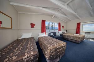 a hotel room with two beds and a chair at Sea View Motel - Unit 1 in Kaikoura