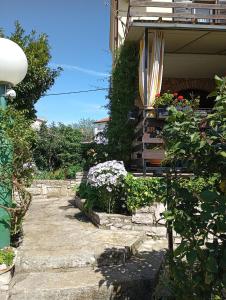 a garden with flowers and a house with an umbrella at Apartments with a parking space Liznjan, Medulin - 11152 in Ližnjan