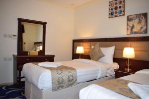 a hotel room with two beds and a mirror at Al Muhajer Serviced Apartments in Al Salamah District in Jeddah