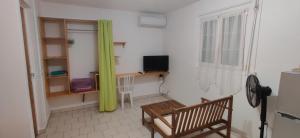una camera con una sedia, un tavolo e una TV di Bungalow Touloulou (Mi) à 10mn à pieds des plages a Le Gosier
