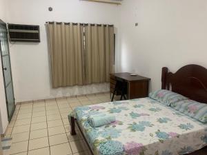 a bedroom with a bed and a desk in it at Suíte com ar-condicionado (Família Hassan) in Corumbá