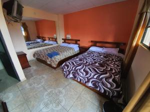 - 2 lits dans une chambre aux murs orange dans l'établissement Hostal La Cocha, à Latacunga