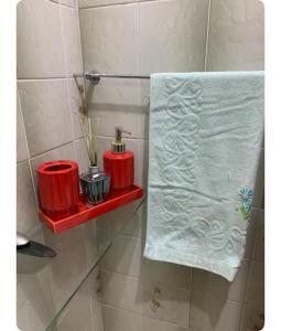 Baño con 2 estanterías rojas y una toalla en Suíte com ar-condicionado (Família Hassan), en Corumbá