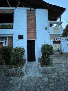 un edificio blanco con una puerta y dos arbustos en Hosteria Puerta del Nus en Cisneros