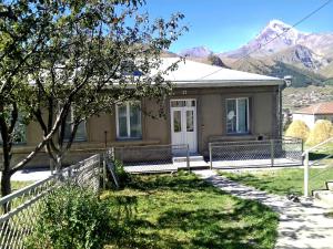 una casa con recinzione e montagne sullo sfondo di Family Hotel 7 Sisters a Kazbegi