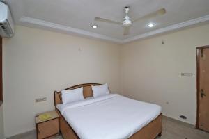 Schlafzimmer mit einem Bett mit weißer Bettwäsche und einer Decke in der Unterkunft Flagship Hotel Capital in Raipur