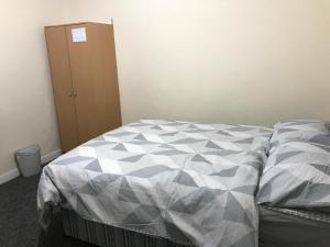 a bed with a comforter and a cabinet in a room at Private double rooms near City centre, Coventry with free Parking/WiFi in Coventry