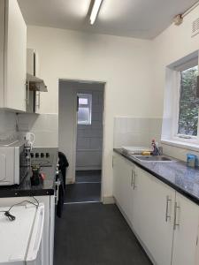 a kitchen with white cabinets and a sink and a window at Private double rooms near City centre, Coventry with free Parking/WiFi in Coventry