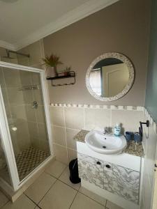 a bathroom with a sink and a shower and a mirror at Marina View in Jeffreys Bay