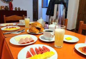 a table with plates of food and glasses of orange juice at Munay Ñusta Cusco in Cusco