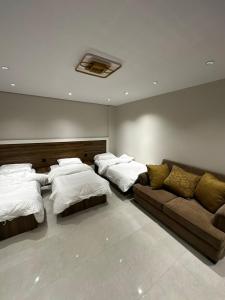 Zimmer mit 3 Betten und einem Sofa in der Unterkunft الماقروف للوحدات السكنيه in Medina