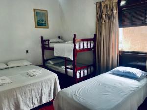 a room with two twin beds and a window at Hostel Pé na Areia in Itanhaém