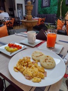 einen Teller Eier und Brot und ein Glas Orangensaft in der Unterkunft Boutique Portón De Granada in Cali