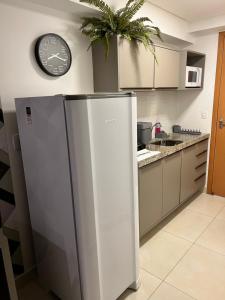 a refrigerator in a kitchen with a clock on the wall at GOLD FLAT MANAÍRA 1705 in João Pessoa