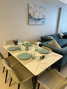 a table with green plates and chairs in a living room at Amazing brand-new apartment in Abdoun! in Amman