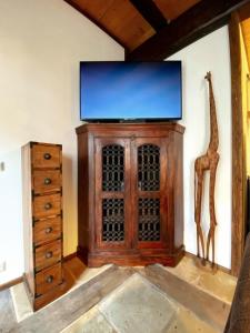 a room with a tv and a cabinet and a giraffe statue at Ferienhaus Namibia-Lodge im Rittergut Leppersdorf in Leppersdorf